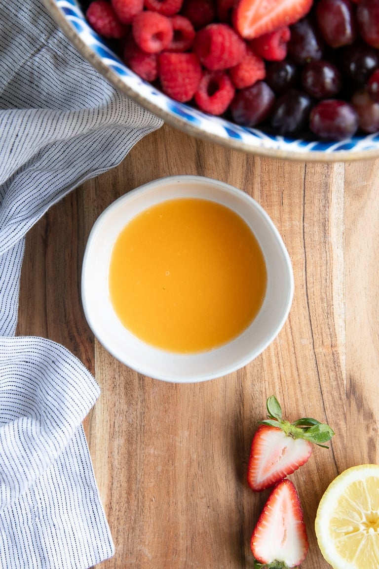 Small white bowl filled with a simple dressing for fruit salad.